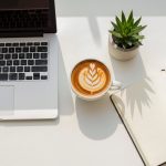 Minimalist home office setup with cappuccino, journal and succulent for remote work, modern minimalist workspace theme, concept of productivity, business, and creative freelance lifestyle